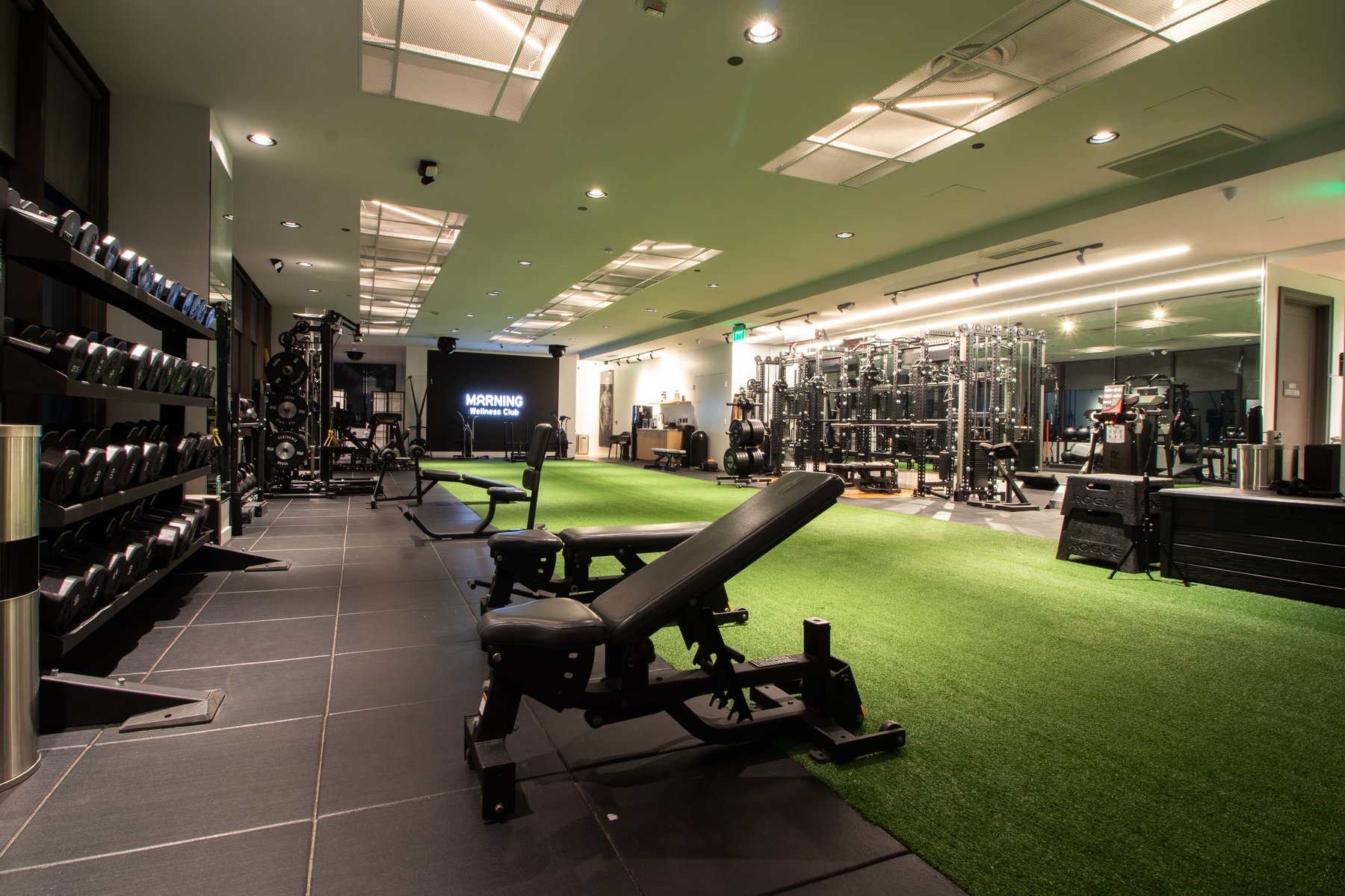 Morning Wellness Club — the training floor with turf, racks, and branded wall